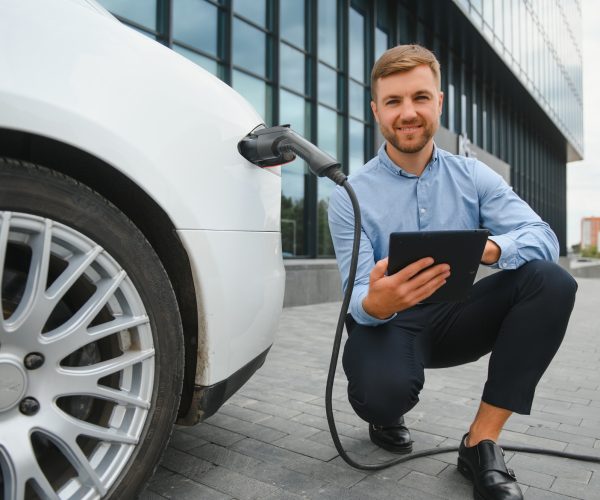 Man charges an electric car at the charging station